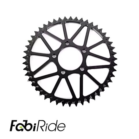 Juodas elektrinis krosinis motociklas geltonais akcentais žalios dirbtinės žolės sienos fone.